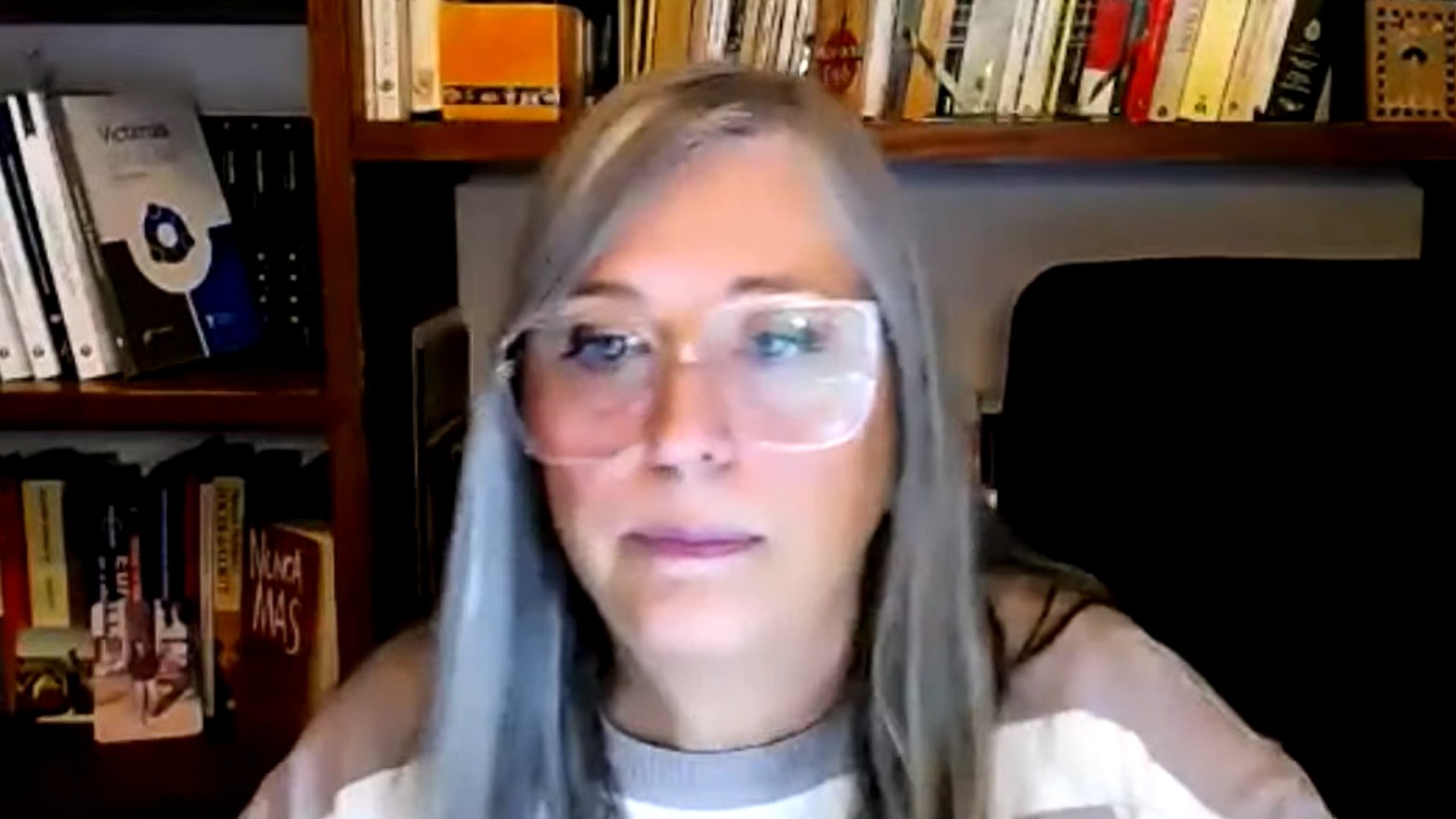 Diana M&aacute;rquez durante la masterclass, frente a la c&aacute;mara, con una biblioteca detr&aacute;s.